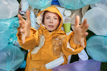 Unpleasantly surprised caucasian woman drowning in a pile of garbageの写真素材