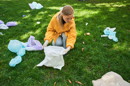 Female eco activist collecting garbage and carrying bin bagsの写真素材