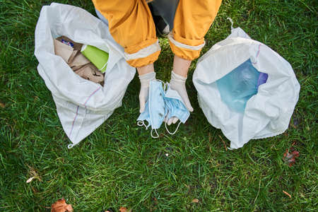 Woman collecting litter and another rubbish in forest while helping to our environmentの写真素材