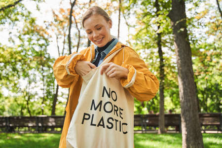 Woman taking something from her eco bag while standing at the parkの写真素材