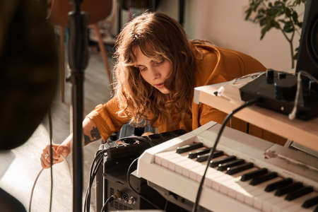 Cute girl adjusting her piano while preparing playing at homeの写真素材