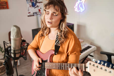 Charming musician in domestic clothes enjoying creative hobbyの写真素材