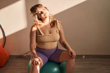 Happy full sized woman exercising at home at the fitness ballの写真素材