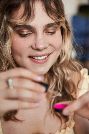 Woman making vivid makeup at home and putting special drops at her cosmeticの写真素材