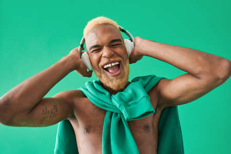 Smiling man touching headphones with hands and screaming in front of the camera