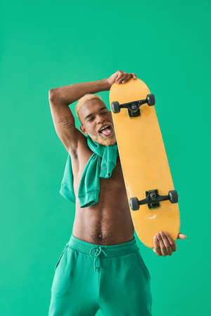 Multiracial young man holding skate at his arms and showing funny faceの写真素材
