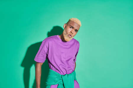 Blonde guy in stylish clothes looking at the camera and grimacing while posingの写真素材