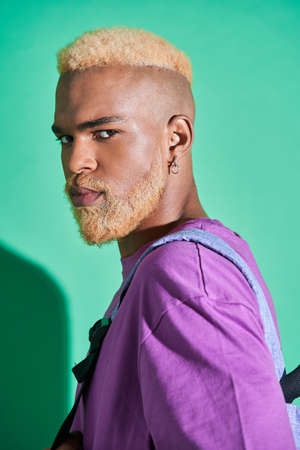 Dark skinned guy with blonde hair holding backpack and looking at the cameraの写真素材