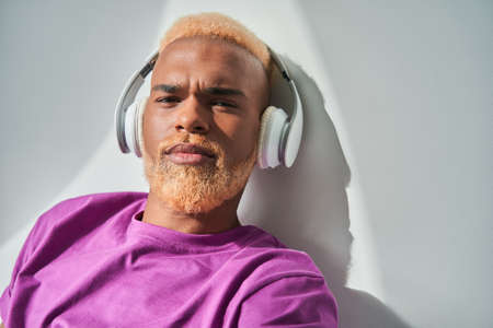 Calm multiracial gentleman with blonde curly hair looking seriously at the cameraの写真素材