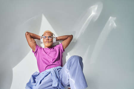 Guy with blonde curly short hair listening music and sitting with closed eyesの写真素材