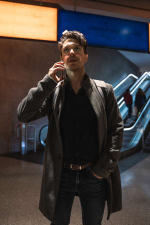 Businessman using smartphone while having call with somebody at the airport at the evening