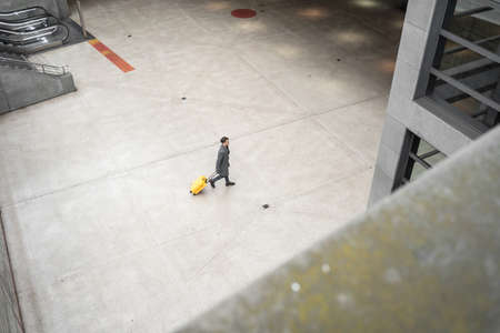 Serious man walking with suitcase to the departure loungeの写真素材