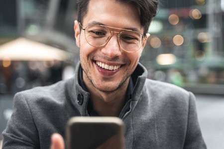 Man looking at the smartphone screen while sitting at the street cafe during his journey