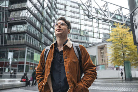 Man looking at different architecture while standing with backpack at the urban settings