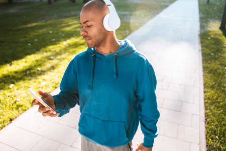 Man wearing casual clothes standing at the street and looking at his smartphone