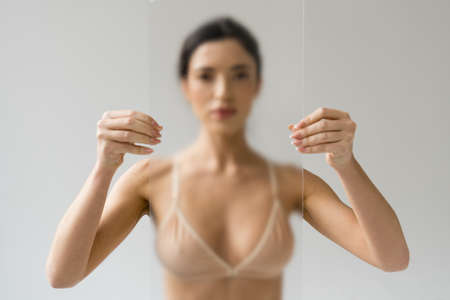Female model posing with transparent glass on white background
