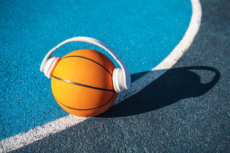 Basketball ball in wireless headphones standing at the stadium ground during the sunny dayの写真素材