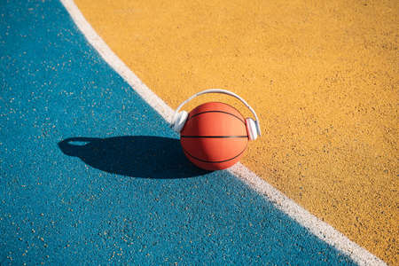 Orange ball in white modern headphones laying at the colored track at the streetの写真素材