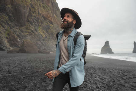 Male traveler meeting dawn at the beach near the mountains in autumn