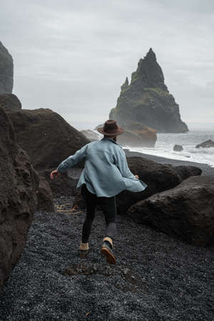 Man running and rejoicing at the sandy black coastline at the Iceland