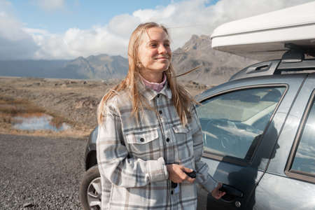 Female person smiling while looking at the distance before the sitting at the car