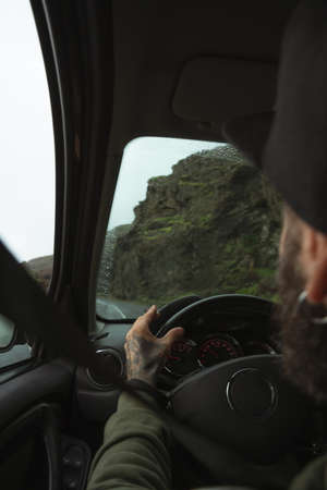 Man driving his car while traveling through the Iceland during the cloudy weatherの写真素材