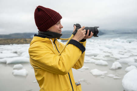 Female photographer taking pictures of the ice and snow during her trip at the Icelandの写真素材