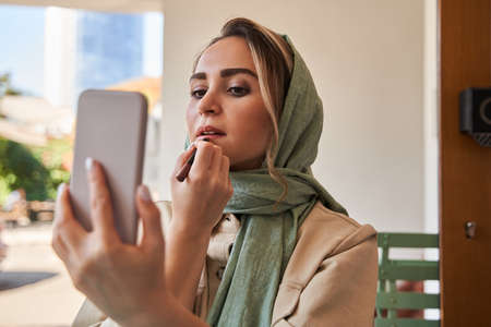Muslim woman wearing hijab looking at the selfie camera at her smartphone