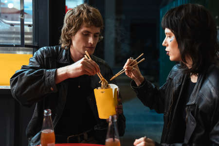 Happy lovely informal couple enjoying food in street cafe