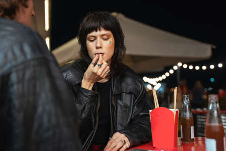 Relaxed female person sitting at the cafe with her boyfriend and smoking cigaretteの写真素材