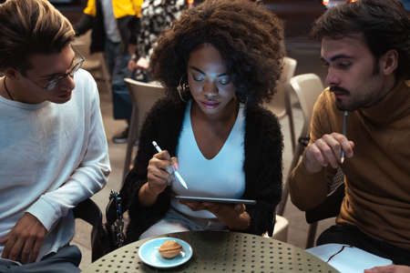 Diverse colleagues working overtime in the urban cafe to finish the projectの写真素材