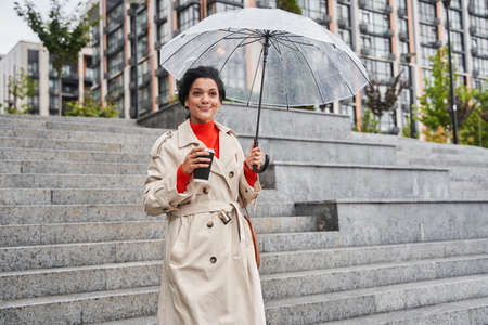 Cheerful pretty girl holding umbrella while strolling outside