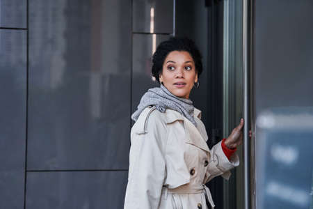 Brunette woman looking over her shoulder while standing at street near the shopping mall