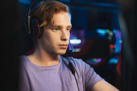 Player with headphones playing at popular online game while sitting with serious faceの写真素材