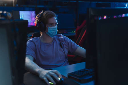 Caucasian guy playing at the online games at his computer and looking concentrated