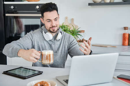 Man having online consultation with somebody while drinking morning coffee at home