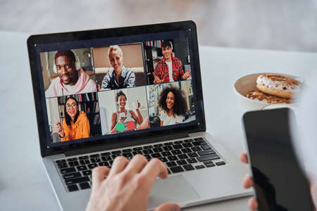 Unrecognizable man using his laptop computer while having zoom callの写真素材