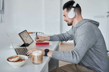 Caucasian man making notes while having video call with colleagues