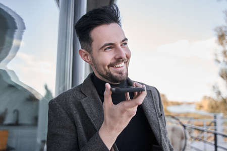 Businessman smiling and recording voice message at his mobile phoneの写真素材