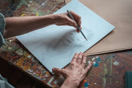 Creative professional female artist painting in her room, while sitting at the tableの写真素材