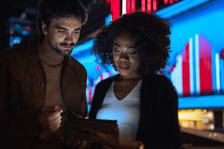 Man looking at the device screen with his multiracial business partner