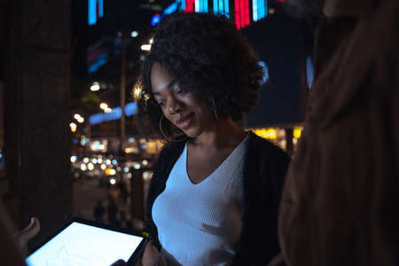 Woman looking at the tablet screen with pleasure smile while working with her colleaguesの写真素材