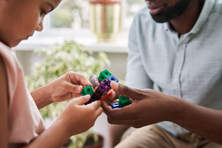 Family of multiracial father and daughter sitting at the bedroom and playingの写真素材