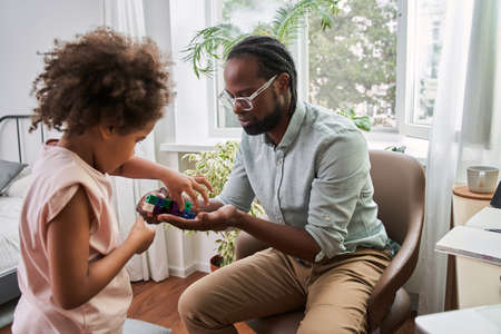 Multiracial man and his daughter are playing together at homeの写真素材