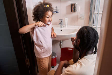 Positive father and daughter in the bathroom washing and brushing teethの写真素材