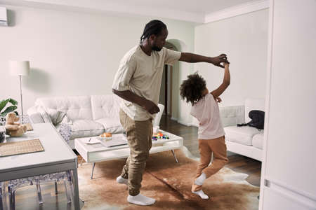 Multiracial father dancing together to favorite music with his little daughterの写真素材