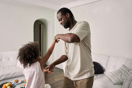 Multiracial father holding hands of his little daughter while dancing togetherの写真素材