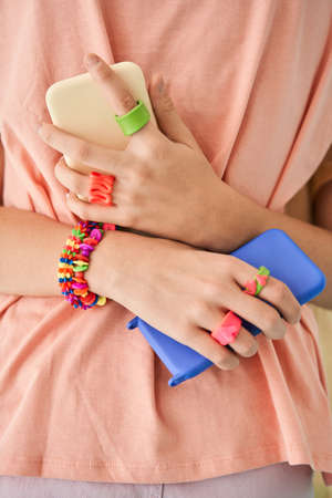 Female child person embracing her sister while holding two smartphones at the each handsの写真素材