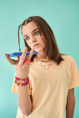 Internet addicted teen girl in creative look recording voice message at her mobile phone