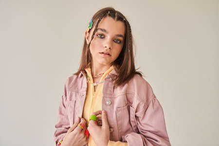 Girl wearing jacket and bright accessorizes looking at the camera with serious faceの写真素材